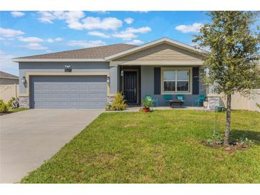 Charming single-story home with a well-maintained lawn and a cozy front porch seating area at 1399 Lassen St, Haines City, FL 33844