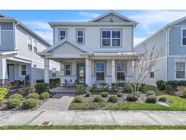 Charming two-story home with landscaped front yard and inviting covered porch with seating at 14317 Lanikai Beach Dr, Orlando, FL 32827