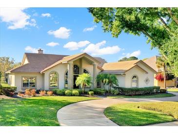 Beautiful single-story home with a circular driveway and manicured landscaping under a partly cloudy blue sky at 2230 Lake Crescent Ct, Windermere, FL 34786