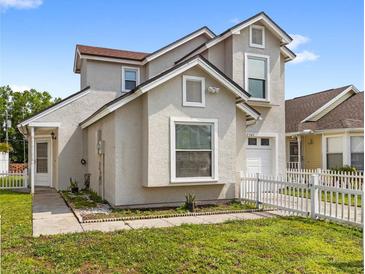 Charming two-story home featuring stucco siding, white picket fence, and well-maintained front yard at 2361 Carriage Run Rd, Kissimmee, FL 34741