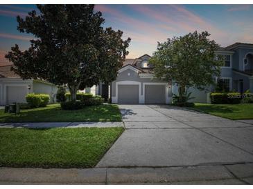 Charming home featuring a two-car garage, well-manicured lawn, and mature trees enhancing curb appeal at 2631 Archfeld Blvd, Kissimmee, FL 34747