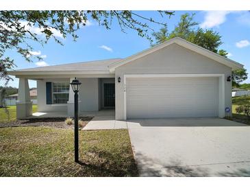 Charming single-story home with a two-car garage, manicured lawn, and inviting curb appeal at 328 Woodland Trl, Lady Lake, FL 32159