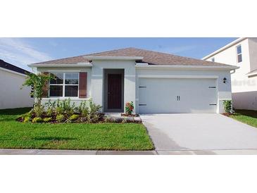 Charming single-story home with a two-car garage, complemented by green grass and landscaping at 3925 Diving Dove Ln, Bartow, FL 33830
