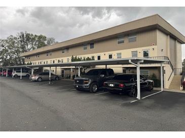 Tan two-story apartment building with covered parking in a well-maintained community at 400 E Orlando Ave # 10 C, Ocoee, FL 34761