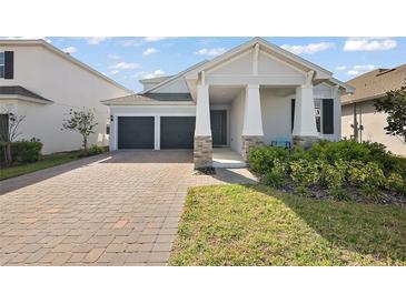 Charming home featuring a two-car garage, a well-maintained yard, and stone pillar details on the front porch at 4439 Davos Dr, Clermont, FL 34711