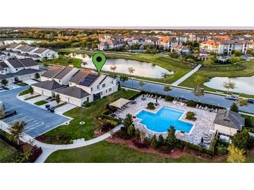 Stunning aerial view of a townhome with solar panels, a community pool, and a scenic pond at 6024 Soter Ln, Windermere, FL 34786