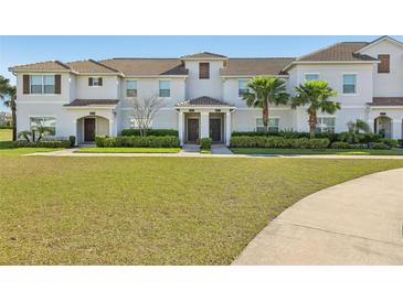 Well-manicured townhouse with lush green lawn, featuring a covered entryway and mature palm trees at 8959 Stinger Dr, Champions Gate, FL 33896