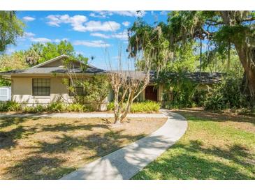 Charming single-story home featuring mature trees and a welcoming walkway on a sunny day at 1511 Grandview Blvd, Kissimmee, FL 34744