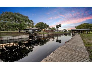 Waterfront home with dock, covered boat lift, and calm canal views under a beautiful dusk sky at 2072 Starboard Dr, Geneva, FL 32732