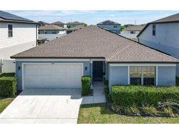 Charming single-story home features a two-car garage and manicured front lawn with lush landscaping at 297 Citrus Isle Loop, Davenport, FL 33837