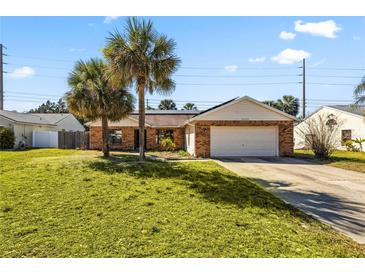 Charming brick home featuring a two-car garage and lush, green lawn with palm trees at 3093 S Horizon Pl, Oviedo, FL 32765