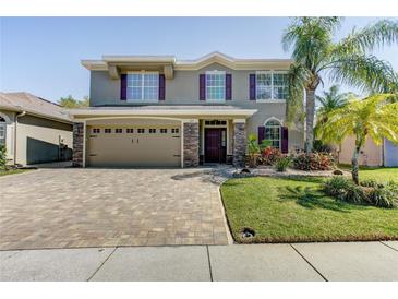 Charming two-story home with a brick driveway, palm trees, manicured lawn, and neutral paint with purple shutters at 321 Cape Sable Dr, Orlando, FL 32825