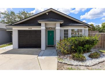 Charming single-Gathering home with a dark brown garage door and vibrant green front door at 4458 Goldenrain Ct, Orlando, FL 32808