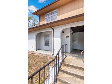 Exterior entrance showcasing the staircase, stucco wall, and a covered walkway leading to the main entrance at 4825 Lighthouse Cir # 4825, Orlando, FL 32808