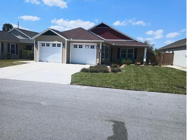 Inviting home with a well-manicured lawn, lush landscaping, and a two-car garage, offering great curb appeal at 5430 Samuel St, The Villages, FL 32163