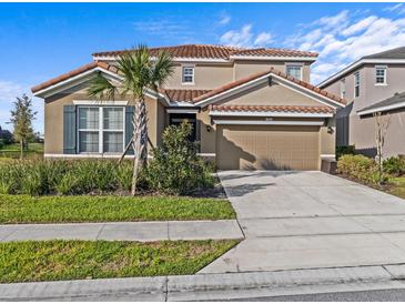 Inviting two-story home featuring a tile roof, manicured lawn, and an attached two-car garage at 7805 Oak Reflection Loop, Davenport, FL 33837