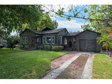 Charming single-story home features dark siding, manicured lawn, and a brick driveway, exuding curb appeal at 1432 W Yale St, Orlando, FL 32804