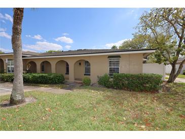 Charming, single-story home featuring arched entryway, manicured shrubs, and a lush green lawn under a bright, sunny sky at 209 Esplanade Way # 109, Casselberry, FL 32707