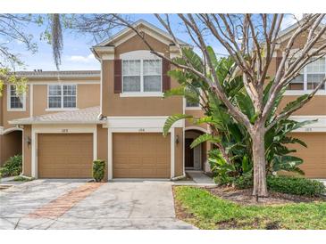 Charming two-story townhome featuring a tan stucco exterior, attached garage, and mature landscaping for added curb appeal at 2864 Polana St # 104, Orlando, FL 32835