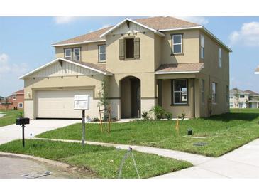 Two-story home with tan siding, attached two-car garage, and landscaped front yard at 13326 Sproston Pt, Orlando, FL 32832