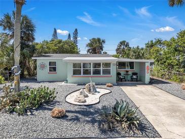 Welcoming curb appeal with rock landscaping, a colorful exterior, and a charming patio seating area on a sunny day at 134 Roberta Rd, Ormond Beach, FL 32176
