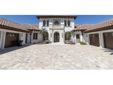 Elegant two-story home featuring a tile roof, white stucco, arched windows and beautiful stone driveway at 14645 Isleview Dr, Winter Garden, FL 34787