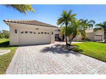 Charming home with a clay tile roof, lush landscaping, and a brick paved driveway leading to a two-car garage at 3403 Great Pond Dr, Kissimmee, FL 34746