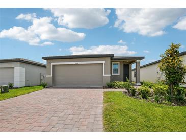 Charming single-story home featuring a paver driveway and beautiful landscaping in the front yard at 4006 Copperleaf Ln, Poinciana, FL 34759