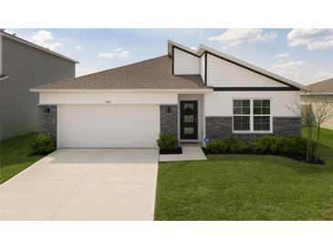 Charming single-story home featuring stone accents, a two-car garage, and a well-manicured lawn at 447 Talisi Loop, St Cloud, FL 34771