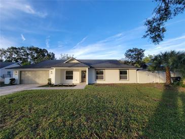 Charming single-story home with a well-maintained lawn and an attached two-car garage under a blue sky at 5153 Lido, Orlando, FL 32807