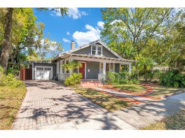 Charming bungalow with a brick driveway, mature landscaping, and inviting front porch at 647 E Livingston St, Orlando, FL 32803