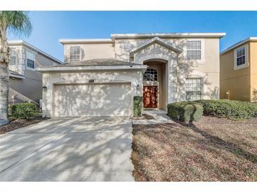 Charming two-story home boasts lush landscaping, a two-car garage and an arched entry at 1028 Orange Cosmos Blvd, Davenport, FL 33837