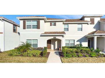 Charming two-story townhome featuring lush landscaping and a welcoming entryway at 1563 Sandbagger Dr, Davenport, FL 33896