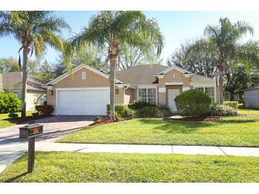 Charming single-story home with a well-manicured lawn, a two car garage, and mature palm trees at 2545 Azzurra Ln, Ocoee, FL 34761