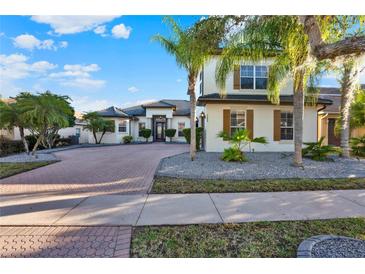 Beautiful two-story home featuring a brick driveway and lush landscaping with palm trees at 2680 Lookout Ln, Kissimmee, FL 34746