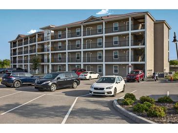 Multi-level tan building with multiple balconies and parking lot in front at 831 Retreat Blvd # 103, Davenport, FL 33897