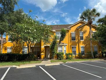 Two story unit with yellow exterior and a parking area with palm trees and nice landscaping at 8843 Villa View Cir # 14-205, Orlando, FL 32821