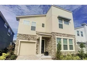 Stylish two-story home showcasing stone accents, neutral stucco, and a convenient attached garage at 9033 Flamingo Key Way, Kissimmee, FL 34747