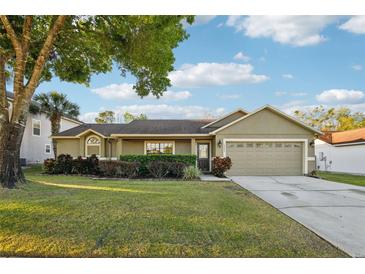 Charming single-story home with a well-manicured lawn, two-car garage, and mature tree providing shade at 1042 Catfish Creek Ct, Oviedo, FL 32765