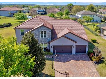 Stunning two-story home showcasing a brick driveway, three car garage, stone accents, and tile roof at 14823 Borromini St, Montverde, FL 34756