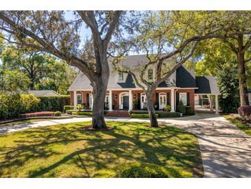 Beautiful brick home with mature trees, circular driveway, and a welcoming front porch; a classic and elegant residence at 1911 Stonehurst Rd, Winter Park, FL 32789