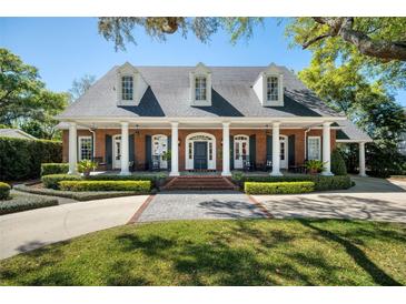 Stunning brick home with a charming front porch, featuring white columns, black shutters, and inviting curb appeal at 1911 Stonehurst Rd, Winter Park, FL 32789