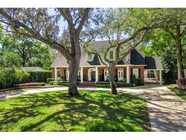 Charming traditional home with a manicured lawn, mature trees, and a welcoming front porch with columns at 1911 Stonehurst Rd, Winter Park, FL 32789