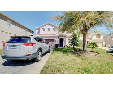 Charming two-story home with a well-maintained lawn, mature tree, and driveway with parked vehicle at 368 Sand Ridge Dr, Davenport, FL 33896