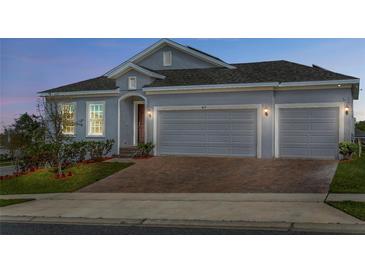 Charming exterior view of a single-Gathering home featuring a two-car garage and a brick driveway at 417 Ironside Trail Dr, Groveland, FL 34736