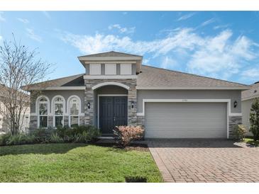 Charming single-Gathering home with a well-manicured lawn and inviting front entrance with stone accents at 4796 Riverwalk Dr, St Cloud, FL 34771