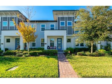 Charming townhome featuring a well-manicured lawn, blue door, and modern architectural details at 5814 Bimini Twist Loop, Orlando, FL 32819