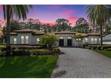 Elegant home featuring lush landscaping, a paver driveway, and a tile roof, showcasing curb appeal at 6424 Cartmel Ln, Windermere, FL 34786