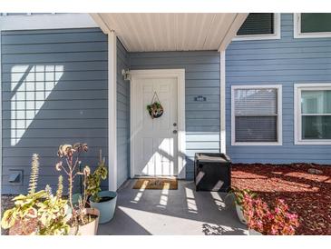 Charming entrance featuring a white door, 'Hello' mat, and potted plants at 729 Secret Harbor Ln # 105, Lake Mary, FL 32746