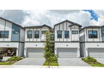 Charming townhomes with two-car garages, and a light gray brick driveway at 10443 Ebb Tide Ln, Orlando, FL 32821